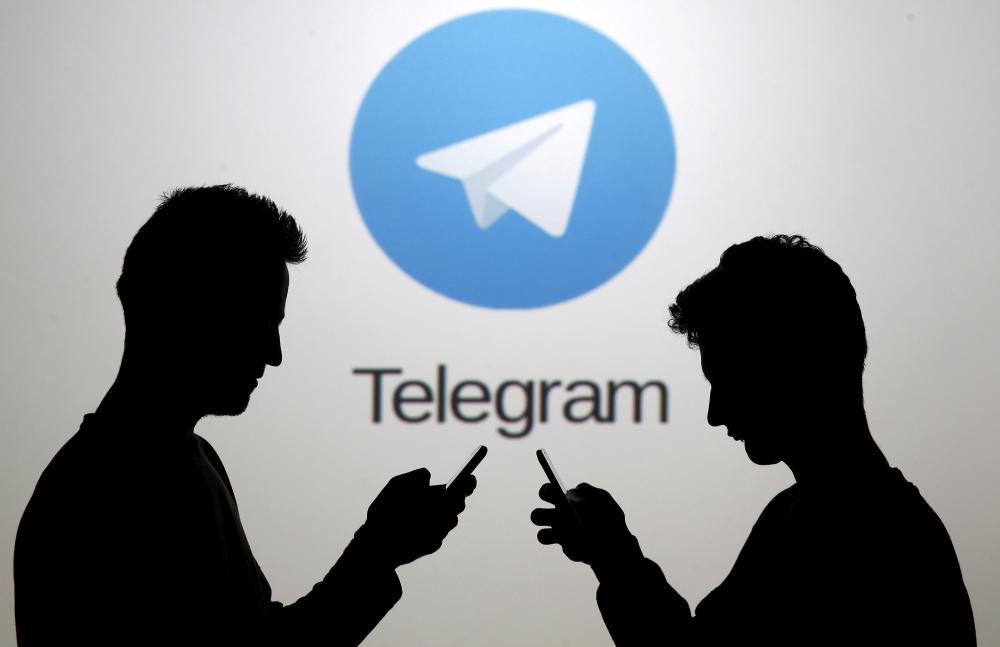 Men pose with smartphones in front of a screen showing the Telegram logo in this picture illustration. — Reuters