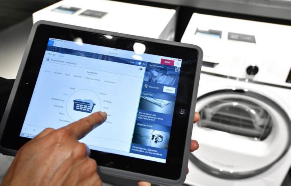 
A fair worker uses a tablet to operate a tumble dryer during a demonstration how to operate smart controlled household appliances for 
