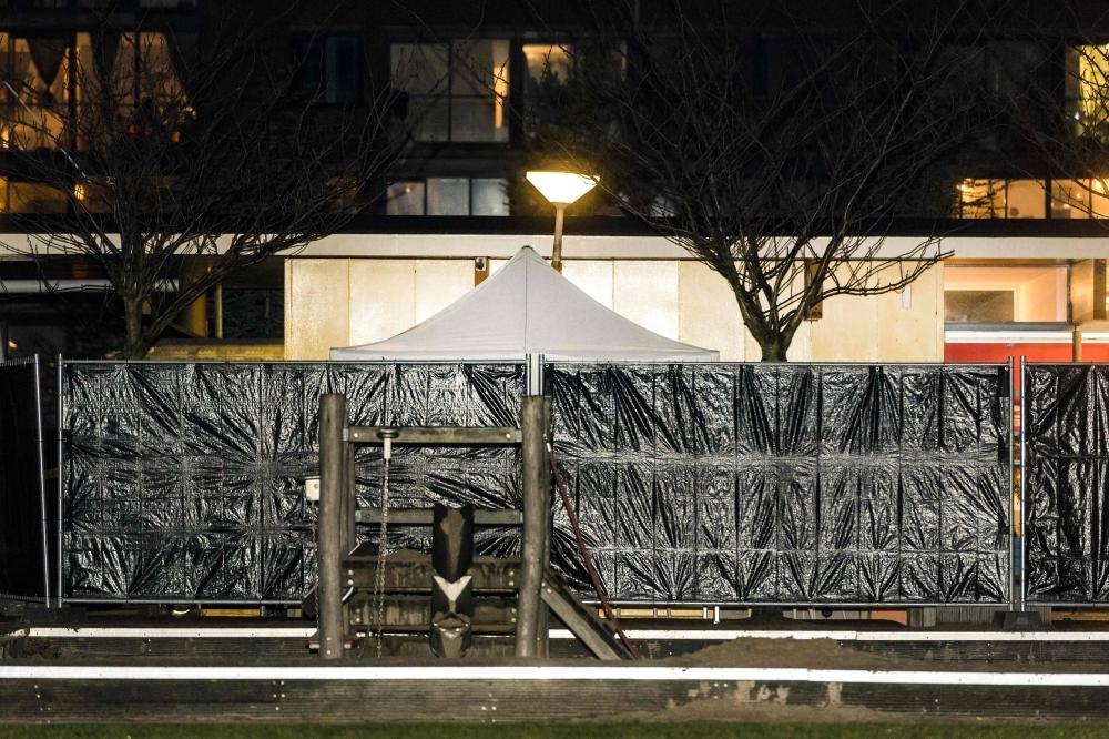 Policemen stand guard at a closed off lane following a shooting at the Grote Wittenburgstraat in Amsterdam on Friday. — AFP 