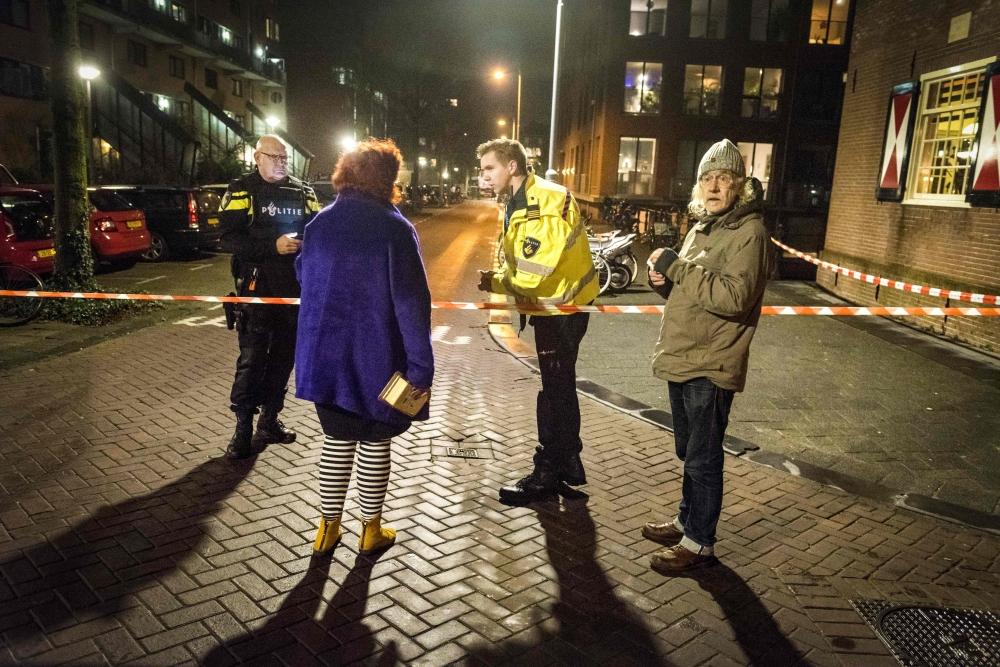 Policemen stand guard at a closed off lane following a shooting at the Grote Wittenburgstraat in Amsterdam on Friday. — AFP 