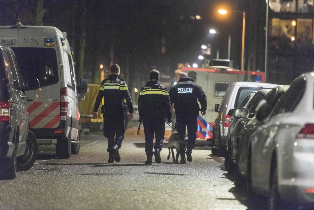 Policemen stand guard at a closed off lane following a shooting at the Grote Wittenburgstraat in Amsterdam on Friday. — AFP 