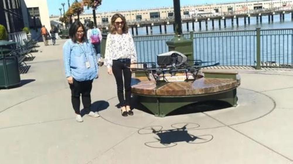 Customers wait as a pizza delivery drone lands in San Francisco on Monday.