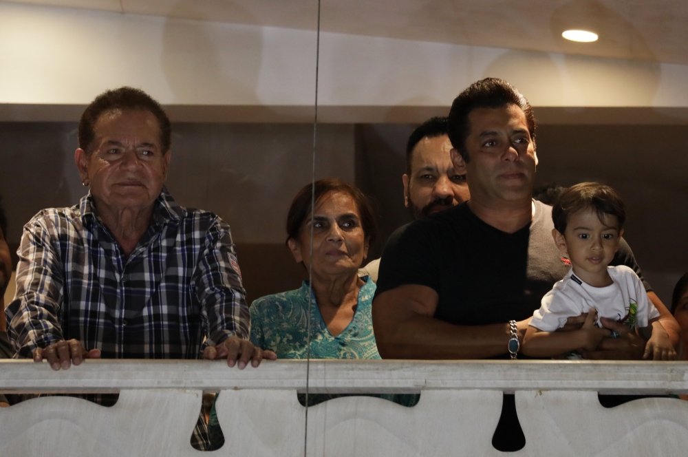 Bollywood actor Salman Khan, right, along with his father Salim Khan and his mother Salma Khan, waves to his fans from his residence in Mumbai on Sunday. - EPA