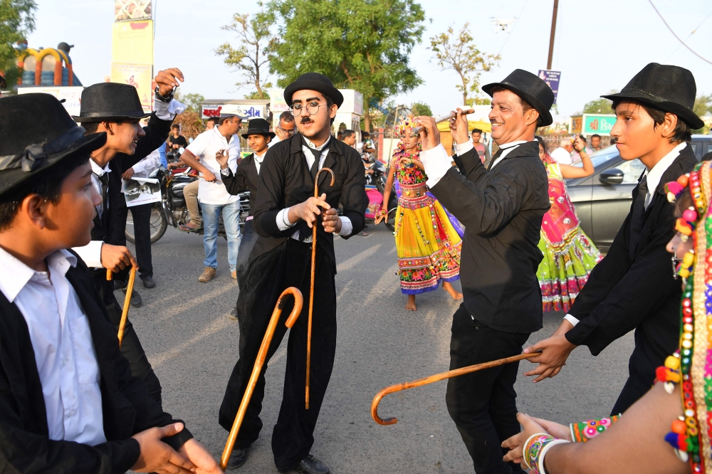 Talin Mavani, center, a Charlie Chaplin impersonator, breaks into a jig with other impersonators during an event commemorating the legendary actor's 129th birthday in Adipur, some 60 km northwest of Bhuj, in the western Indian state of Gujarat on Tuesday. - AFP