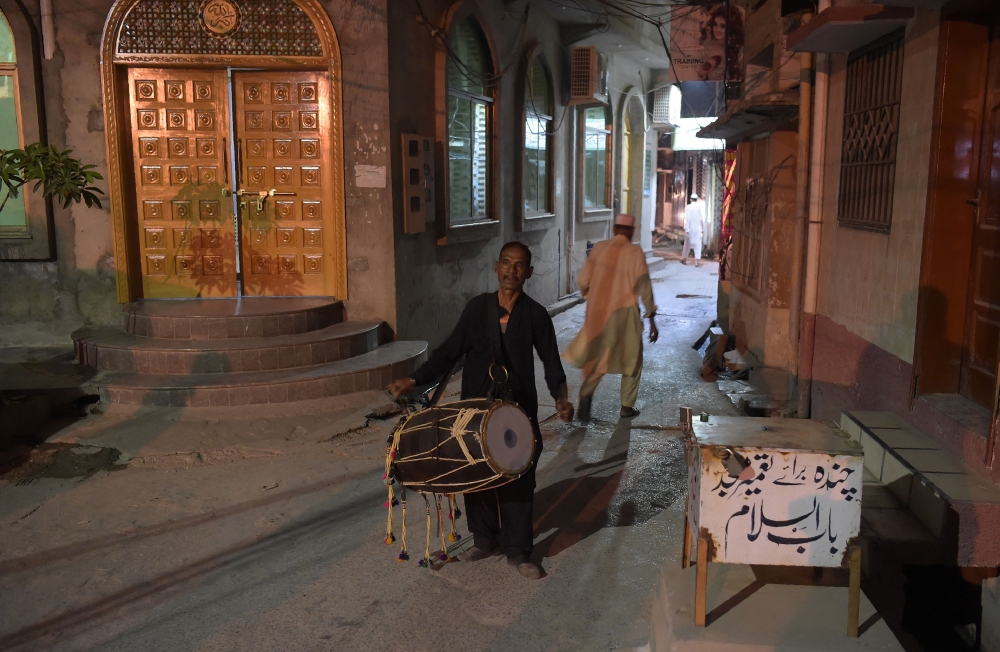 Lal Hussain beats his drum as he makes his way through the alleys of Bani, an old residential area in Rawalpindi, Pakistan. - AFP