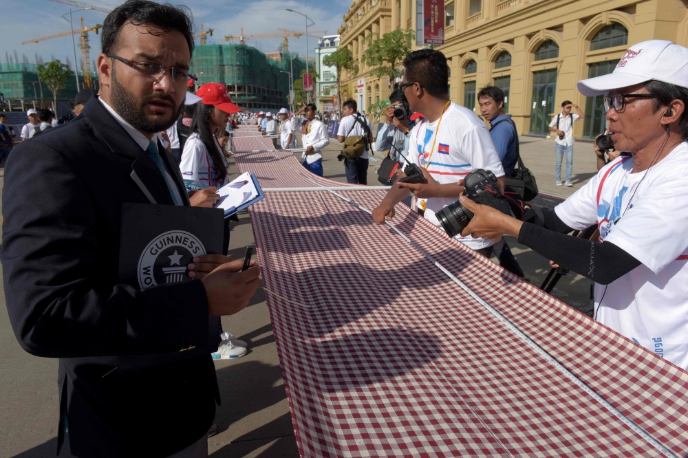Adjudicator Swapnil Dangarikar, an official from the Guinness World Records, left, watches the measuring of the famed hand woven scarf known as Krama for the Guinness World Records in Phnom Penh, Cambodia on Sunday. - AFP