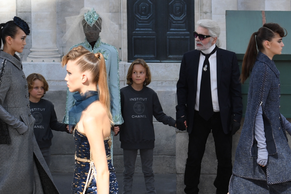 German fashion designer Karl Lagerfeld, right, flanked by his godson Hudson Kroenig, second right, and South Sudanese-Australian model Adut Akech, left, acknowledges the audience at the end of the Chanel 2018-2019 Fall/Winter Haute Couture collection fashion show at the Grand Palais in Paris on Wednesday. - AFP