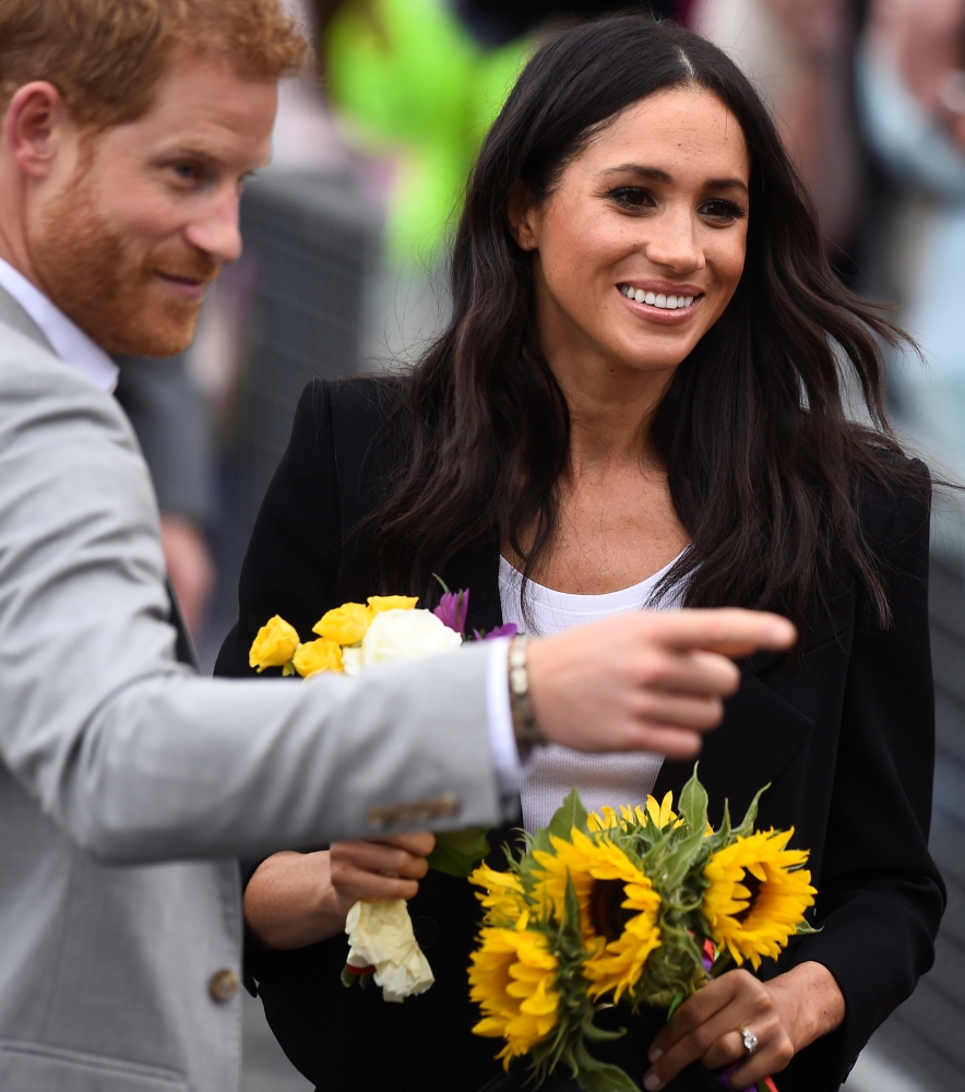 Britain's Prince Harry and Meghan, the Duchess of Sussex, accept flowers during a visit to Parliament Square in Trinity College, Dublin on Wednesday. - Reuters