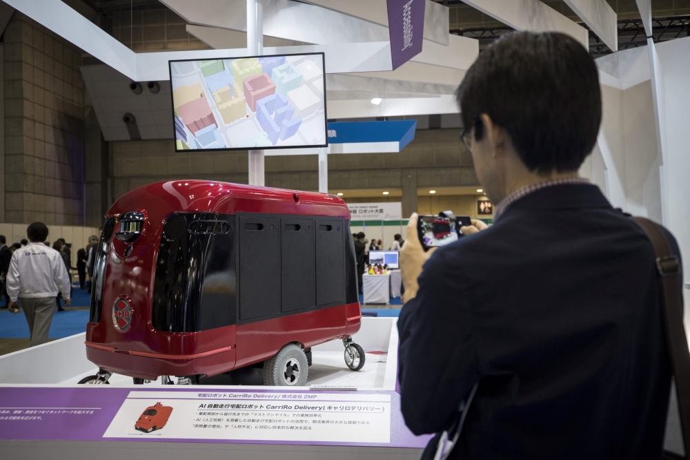 A man takes pictures of a CarriRo robot made by ZMP, which rolls along the pavements and direct itself via GPS to an address within a two-kilometer radius, at the World Robot Summit in Tokyo, on Thursday. — AFP