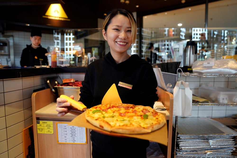 A waiter poses with a durian pizza at La Cesar Pizzaria in Shanghai, China. — Reuters