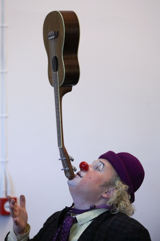 A clown balances an instrument on his chin as he performs ahead of the annual Grimaldi Memorial Service at the All Saints church in east London. — AFP