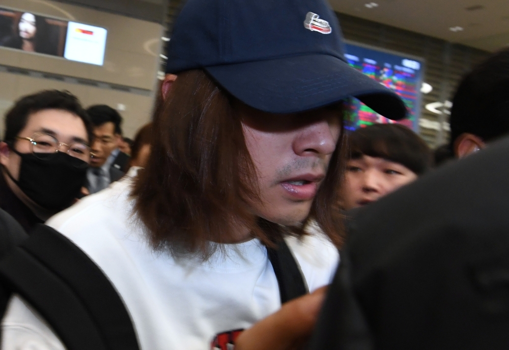 This picture taken on Tuesday shows K-pop star Jung Joon-young (C) surrounded by reporters as he arrives at Incheon international airport in Incheon. — AFP