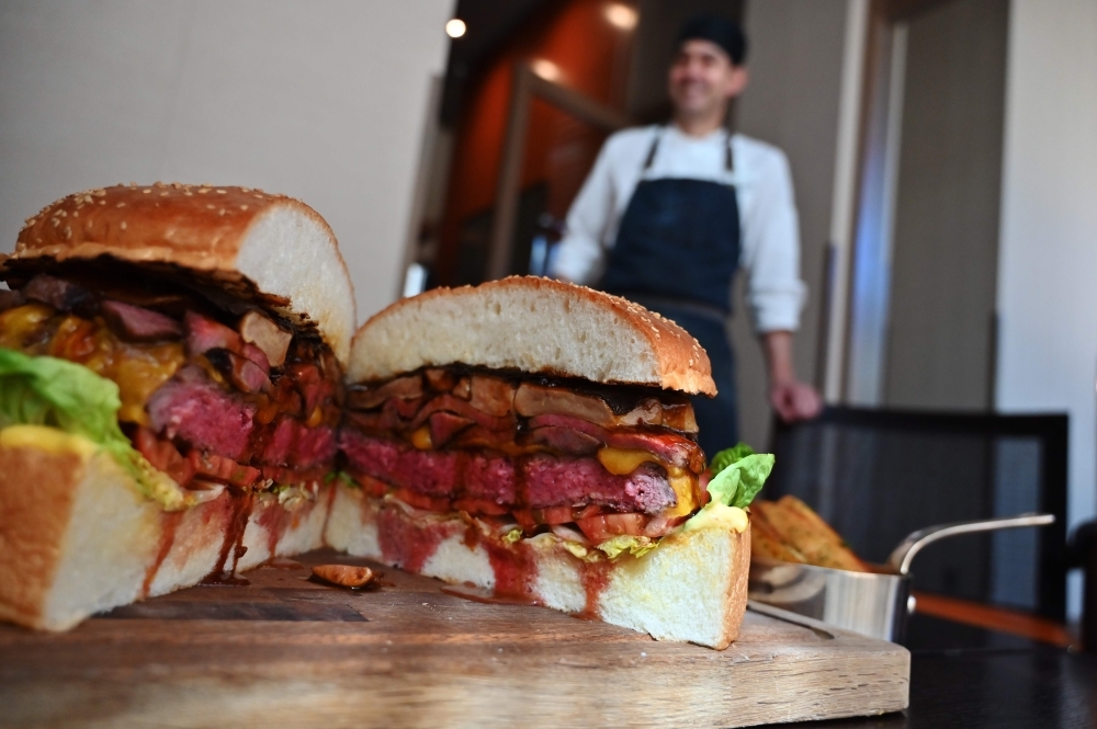 Patrick Shimada, the chef de cuisine at The Oak Door of the Grand Hyatt Tokyo hotel poses with a 3kgs burger in Tokyo Monday. — AFP