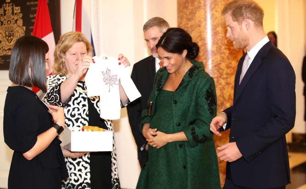 Meghan, Duchess of Sussex (2R) and Britain's Prince Harry, Duke of Sussex (R), react as they are presented with baby gifts by Canadian High Commissioner to the United Kingdom, Janice Charette (2L), at Canada House, the offices of the High Commision of Canada in the United Kingdom, during an event to mark Commonwealth Day, in central London. — AFP file photo