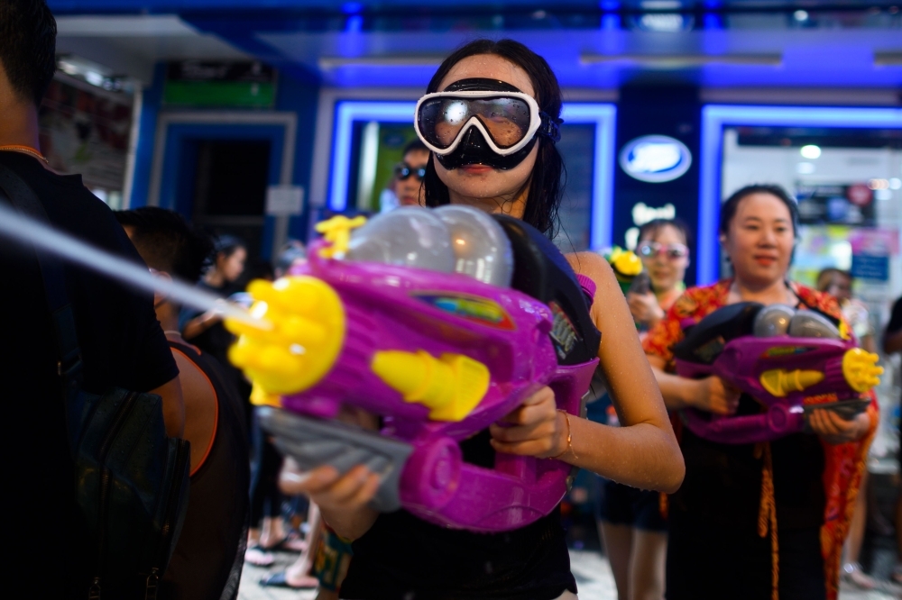 Revelers use water guns to spray at one another as they celebrate the Buddhist New Year, locally known as Songkran, in Bangkok on Sunday. — AFP