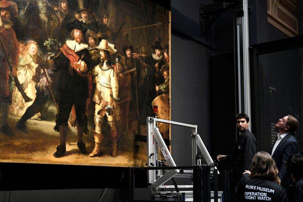 Restorers prepare Rembrandt's famous painting the 'Night Watch', protected by a glass barrier and video surveillance, as it undergoes public restoration after a first phase of study, in Rijksmuseum in Amsterdam, Netherlands Monday. — Reuters