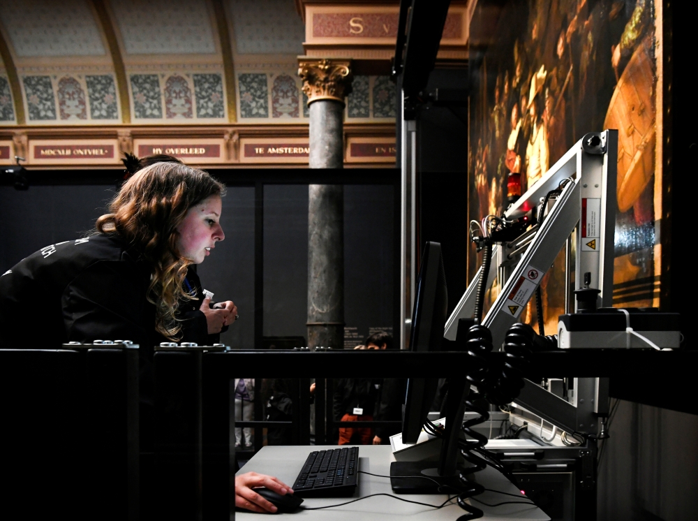 Restorers prepare Rembrandt's famous painting the 'Night Watch', protected by a glass barrier and video surveillance, as it undergoes public restoration after a first phase of study, in Rijksmuseum in Amsterdam, Netherlands Monday. — Reuters
