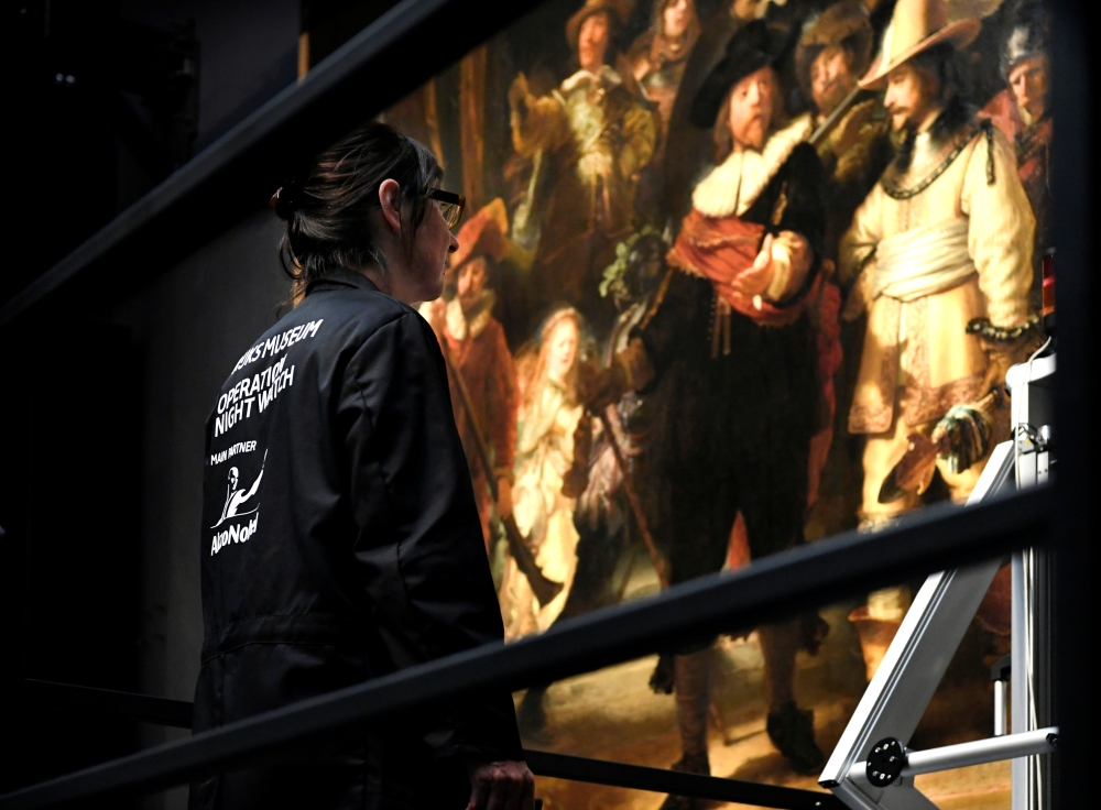 Restorers prepare Rembrandt's famous painting the 'Night Watch', protected by a glass barrier and video surveillance, as it undergoes public restoration after a first phase of study, in Rijksmuseum in Amsterdam, Netherlands Monday. — Reuters