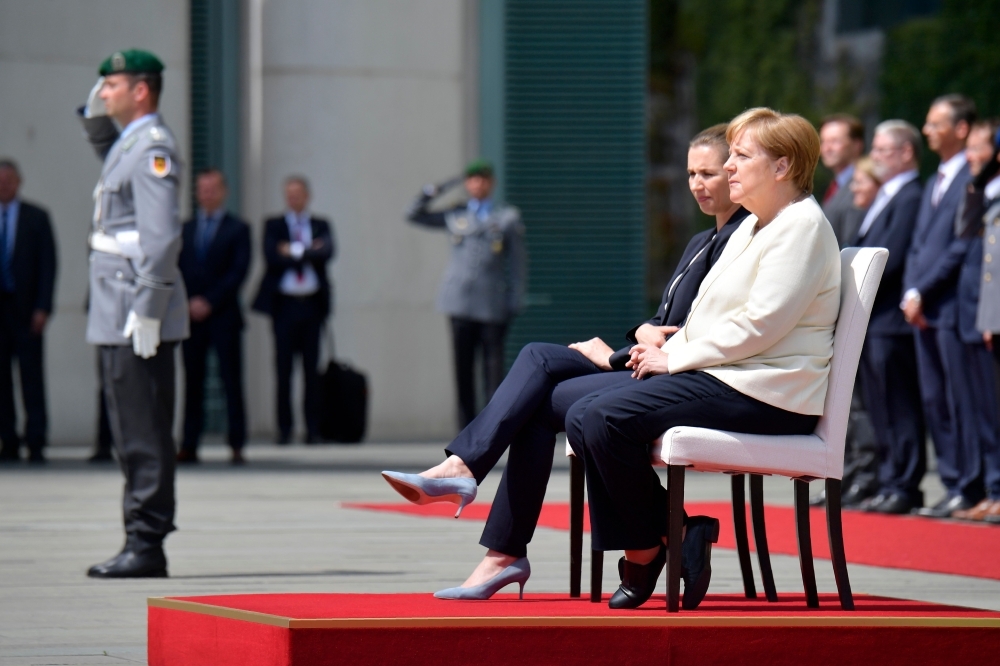 German Chancellor Angela Merkel, right, and Denmark's Prime Minister Mette Frederiksen sit as they listen to the national anthems during a welcoming ceremony with military honors in the courtyard of the Chancellery in Berlin on Thursday. — AFP