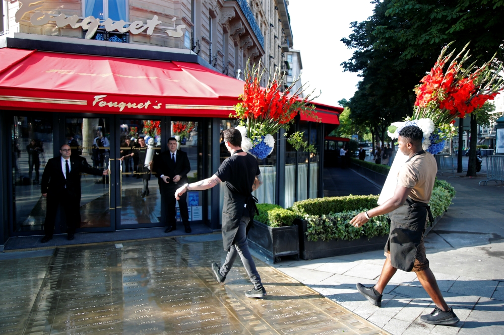 Employees bring flowers to the Fouquet's restaurant on the eve of its reopening on the Champs Elysees, almost 4 months after it was ranksacked by a 