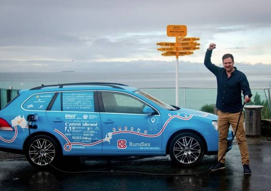 Dutchman Wiebe Wakker holds a charging cable as he poses with his electric vehicle, the Blue Bandit, after traveling 34 countries to reach Bluff, New Zealand's most southern tip, in this handout photo released Friday. — Reuters