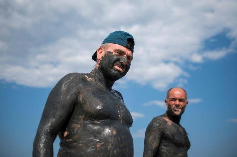 Two people are covered in mud wait for it to dry at the Salt-works lakes near the Black Sea town of Burgas in Bulgaria on Friday. Thousands of tourists visit the red salt lakes for mud baths, which are believed to help the healing of muscular disorders and rheumatism. — AFP