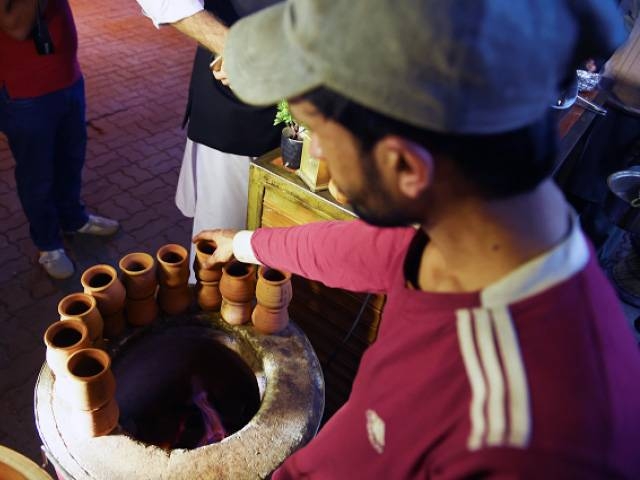 In this picture taken on March 29, 2019, a Pakistani worker places clay pots around a tandoor at a stall of a market in Islamabad. — AFP