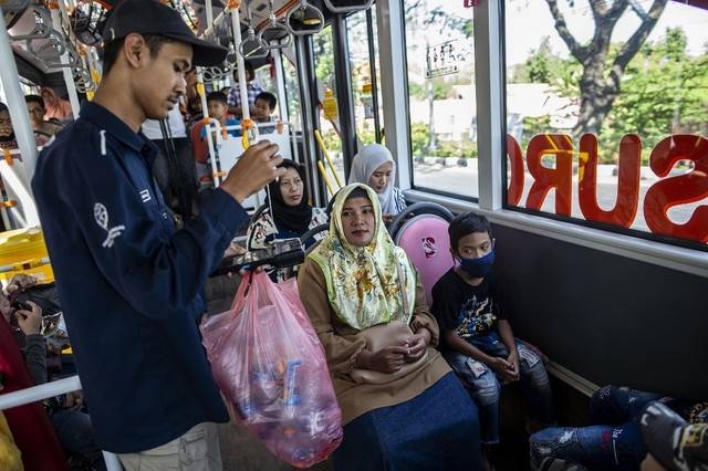 This picture taken on July 21, 2019 shows a bus conductor collecting used plastic bottles as fare payment on board a Suroboyo bus in the Indonesian city of Surabaya. -AFP