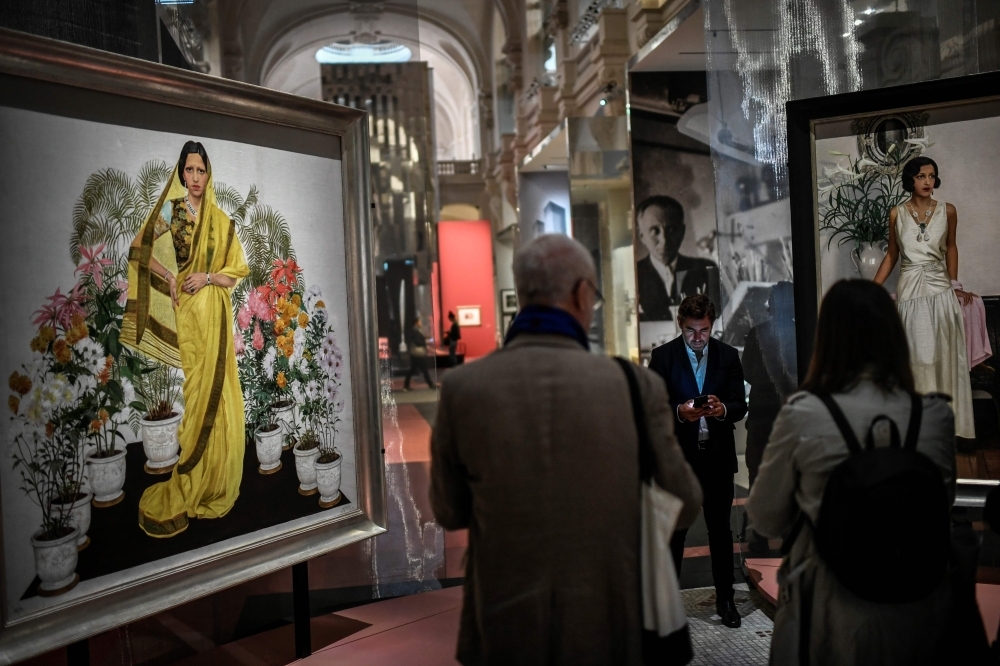 Visitors walk past an painting (1933-1934) showing Indian Maharani Sanyogita Devi of Indore in tradition dress displayed at the opening of 