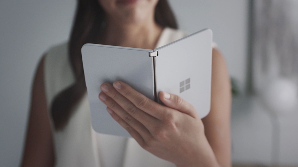 This handout photo obtained Wednesday courtesy of Microsoft shows a woman looking at a new dual-screen device Surface Duo. Microsoft unveiled Surface tablet computers with twin-screens that opened like books, and a notepad-sized version that put it back in the smartphone game. — AFP