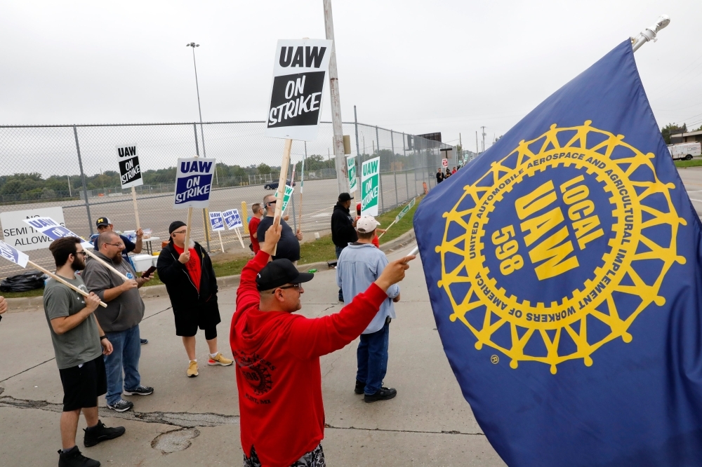 In this file photo taken on Sept. 16, 2019, David Garcia (C) (holding a United Auto Workers (UAW) flag) who is employed at the General Motors Co. Flint Assembly plant in Flint, Michigan, pickets outside of the plant during a strike. As the General Motors strike grinds on, more auto suppliers and contractors are sending workers home, adding to the economic drag on Michigan and other US midwestern car manufacturing hubs. — AFP