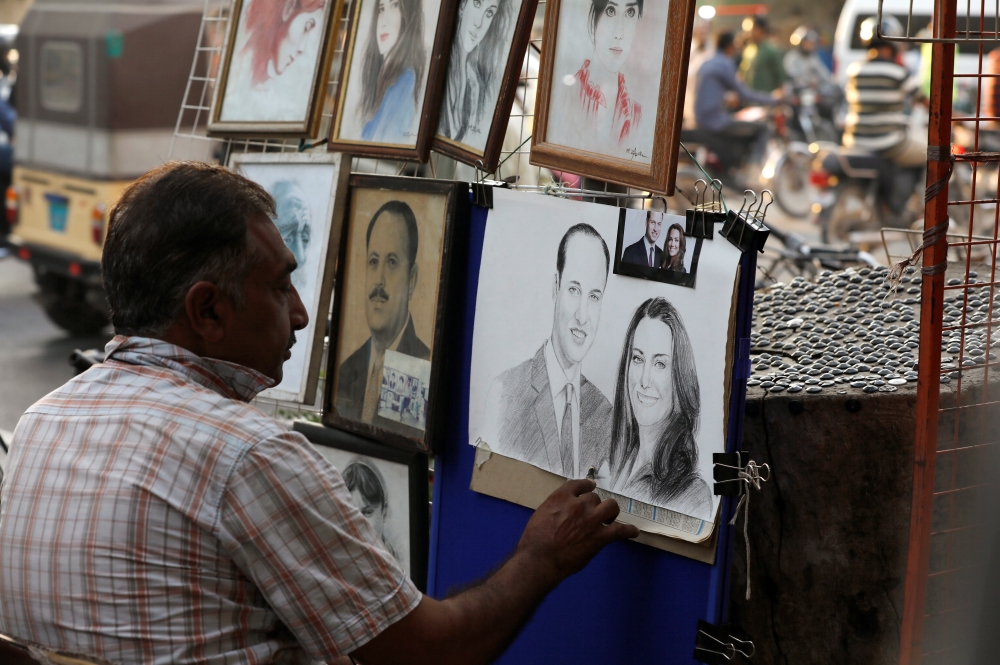 Street artist Mohammad Zaffar, 54, draws a sketch of Britain's Prince William and Catherine, Duchess of Cambridge, ahead of their visit, from a makeshift stall along a sidewalk in Karachi, Pakistan, Friday. — Reuters
