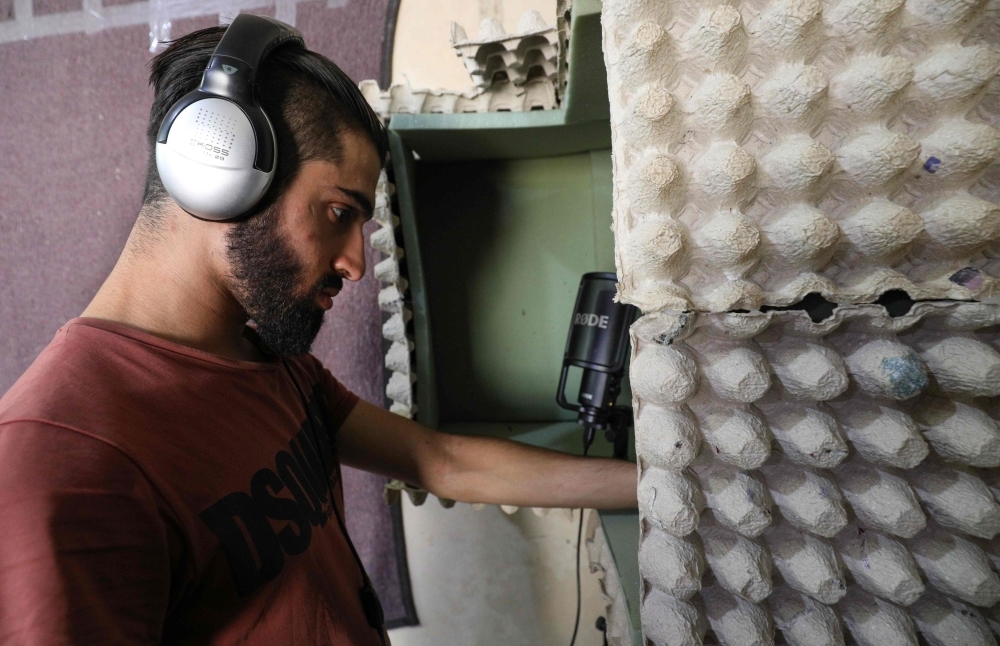 Syrian rapper Amir Al-Muarri works with earphones on, in front of his microphone-equipped booth, padded with soft foam and egg cartons, in his room in the northwestern city of Maaret Al-Numan in the Idlib province in this Sept. 26, 2019 file photo. — AFP