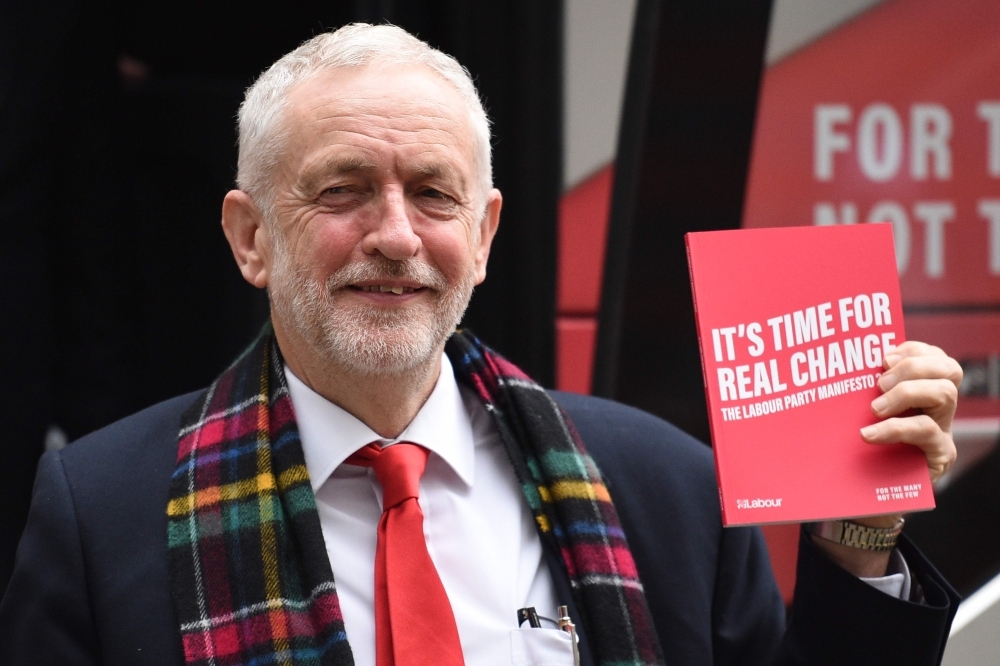 Britain's Labour Party leader Jeremy Corbyn, center, holds up a copy of their general election manifesto with members of his shadow cabinet as he arrives for a manifesto launch event in Birmingham, northwest England, on Thursday. — AFP