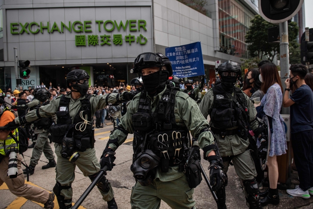 Riot police arrive to disperse people gathering in support of pro-democracy protesters during a lunch break rally in the Kowloon Bay area in Hong Kong on Tuesday. -AFP
