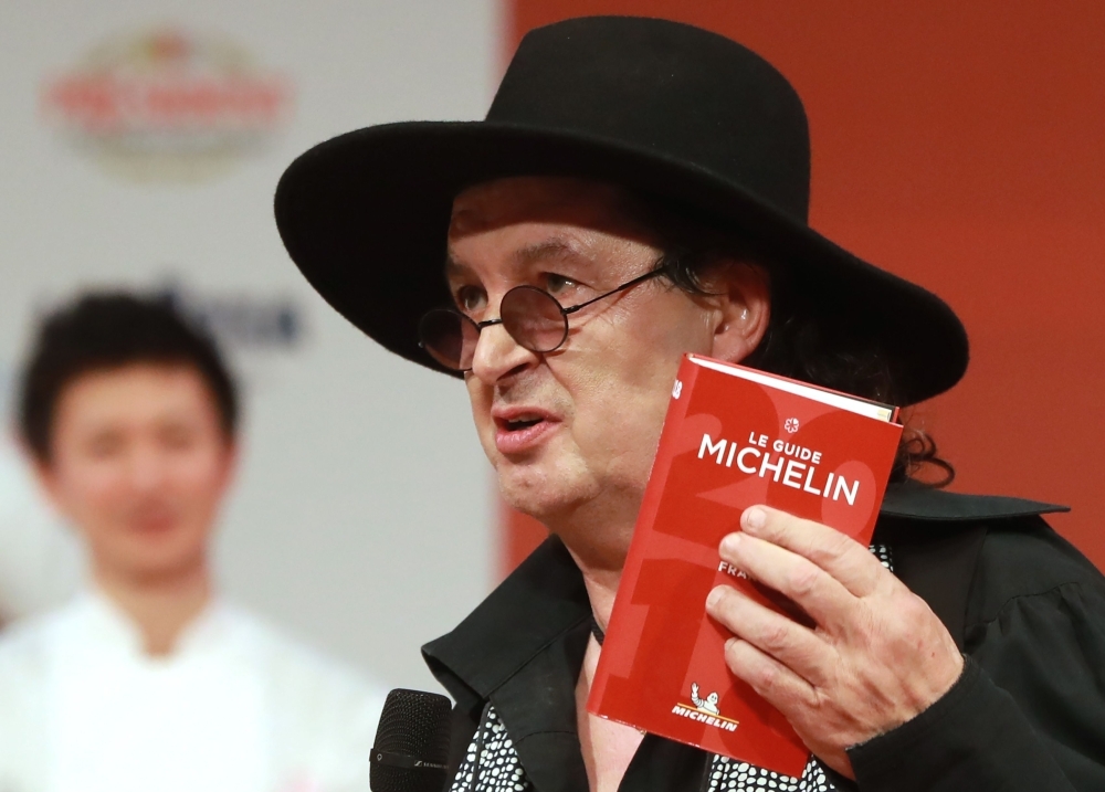 French chef Marc Veyrat holds a Michelin guide after being awarded the maximum three Michelin stars, during the Michelin guide award ceremony at La Seine Musicale in Boulogne-Billancourt near Paris in this Feb. 5, 2018 file photo. — AFP