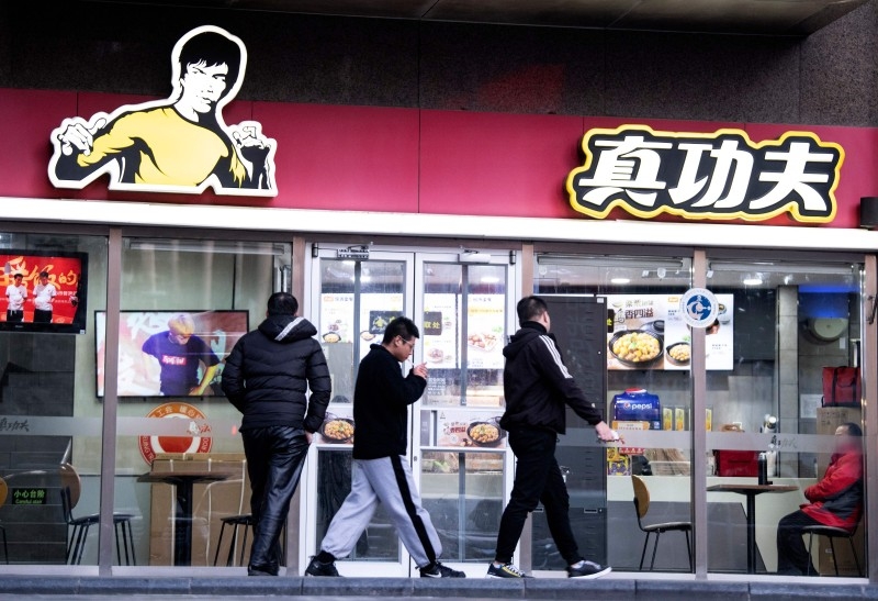 People walk past the restaurant Real Kung Fu, or Zhen Gongfu in Mandarin, run by fast food chain Kungfu Catering Management, in Beijing on Thursday. — AFP