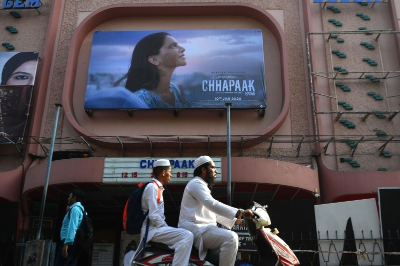 People ride on a scooter past a cinema with a poster for the Bollywood movie Chhapaak in Mumbai on Friday. — AFP