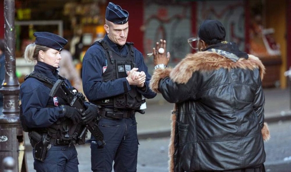 Two French police officers in Paris question a woman after the 6 p.m. curfew on March 17, 2020. — courtesy Daniel Brown/PA.