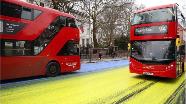 Two buses drive through the yellow and blue paint left by protestors outside the Russian embassy. — courtesy Reuters