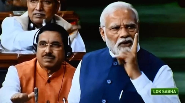 India's Prime Minister Narendra Modi (R) is seen on a television screen as he addresses the lower house Lok Sabha in New Delhi on August 10, 2023