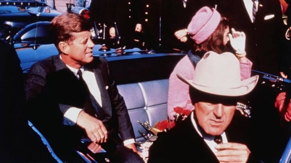 Texas Governor John Connally is seen adjusting his tie in the foreground as John F Kennedy Jackie Kennedy sit in the back seat