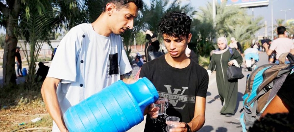 Two men share drinking water in the Gaza Strip. — courtesy UNRWA/Ashraf Amra