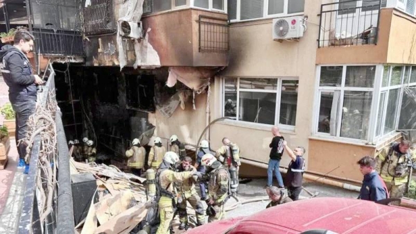 Firefighters crowd around a blackened hollow at the base of a building. — courtesy EPA