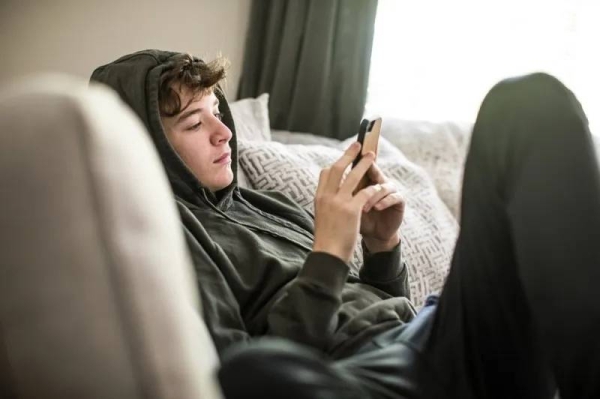 A teenage boy using smartphone at home