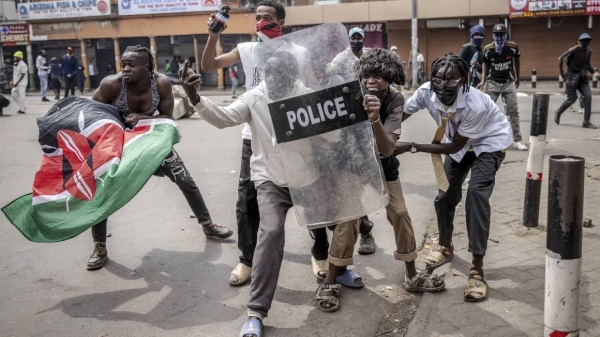 Protesters use a Kenya Police anti-riot shield to protect themselves from tear gas canisters and rubber bullets amid clashes during demonstrations in downtown Nairobi, on July 2, 2024