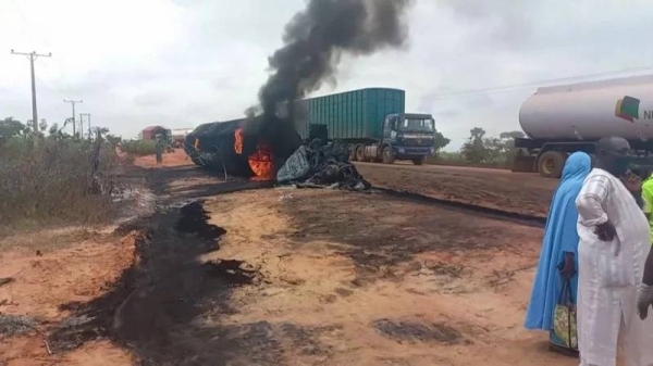 A flaming burnt-out oil tanker lies at the side of the road in the state of Niger