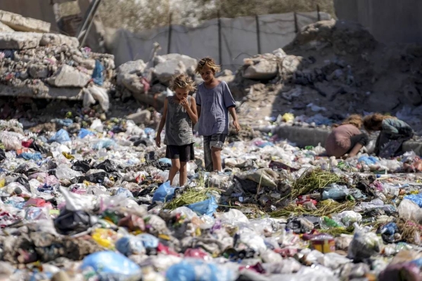 Displaced children sort through trash at a street in Deir Al-Balah, central Gaza Strip, on August 29