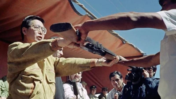 Alberto Fujimori hands out a weapon to a peasant in 1991 to help fight leftist rebels. (File)