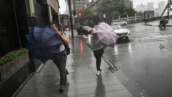 Pedestrians struggle with their umbrellas in strong winds and rain from the passage of Typhoon Bebinca in Shanghai on September 16, 2024